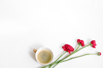 Spring composition with red flowers and cup of coffee on white background. Flatlay, top view, copy space. Feminine morning concept