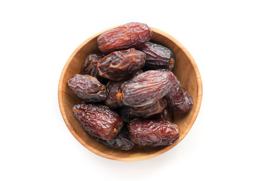 Medjool date fruit isolated in wooden bowl. Top view. 