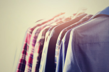 Male clothes, jackets and shirts hanging on clothes rail. Blue color clothes. Copy space. Image with toned effect