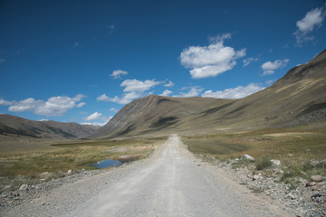 Fototapeta premium Wildlife Altai. The road, mountains and sky with clouds in summer