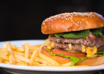 yummy hamburger on white plate with dark background, selective focus