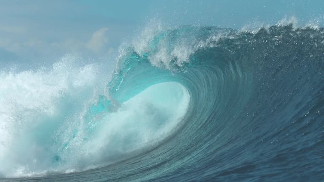 SLOW MOTION, CLOSE UP: Powerful Cloudbreak wave violently swirls in cool sunny weather. Majestic emerald ocean wave crashes on perfect summer day. Giant tube wave breaks violently and glimmers in sun.