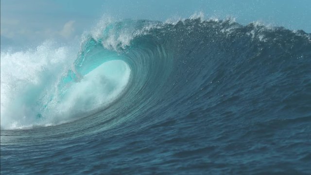 SLOW MOTION, CLOSE UP: Incredible tube wave crashes and glimmers in the bright summer sunlight. Breathtaking ocean wave swirls towards the beach. Massive tropical wave rolls in from the vast ocean.