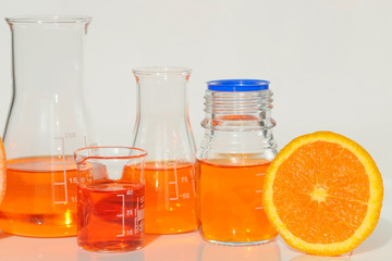 Vitamin C concept.Solution of vitamin C in laboratory flasks and citrus fruits orange  in a cut on a light background.Health and Beauty