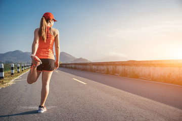 An asian woman athletic is jogging on the concrete road, she is warming her body and tideten her tying her shoes tightly fitting before workout.
