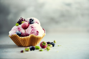 Pink ice cream with berries, strawberries, blueberries, raspberries, pistachios in waffle basket....