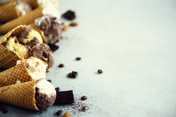 Chocolate and coffee ice cream in waffle cone with coffee beans on grey stone background. Summer food concept, copy space. Healthy gluten free ice-cream. Top view