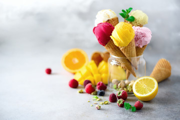 Colorful ice cream balls in waffle cones with different flavors - mango, lime, mint, pistachio, orange, strawberries, raspberries, blueberries. Summer concept - obrazy, fototapety, plakaty