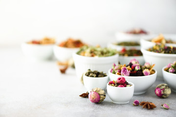 Assortment of dry tea in white bowls. Tea types backgound: green, black, floral, herbal, mint, melissa, ginger, apple, rose, lime tree, fruits, orange, hibiscus, raspberry, cornflower, cranberry