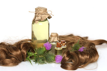 Fototapeta premium Burdock oil set for Hair.Burdock Natural Cosmetics for Hair.plant burdock (Arctium lappa) in brown curls and oil in a glass bottle on a white background.Organic Natural Cosmetics