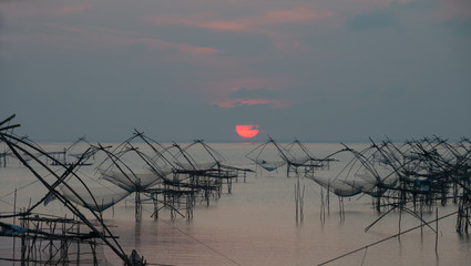 Fototapety  Landmark of traditional fishing net tools in the lake with beautiful morning sunrise at Pakpra village.