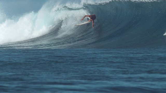 SLOW MOTION: Young pro male surfer attempts to ride a large wave and crashes. Athletic man riding a big barrel wave is thrown off his surfboard and into the crystal clear water on epic summer day.