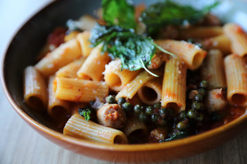 Pasta with sausage in tomato sauce on wood background , italian food