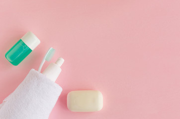 Toothbrushes and toothpaste wrapped in white towel near soap and rinse on pink background. Dental and healthcare concept. Free copy space.