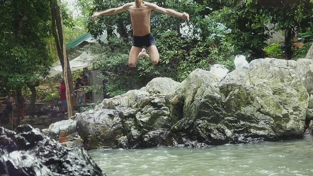 Young man jumps in slow motion in waterfall. 1920x1080