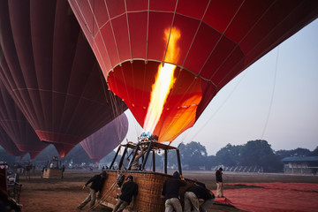 Men fill hot air with red balloons