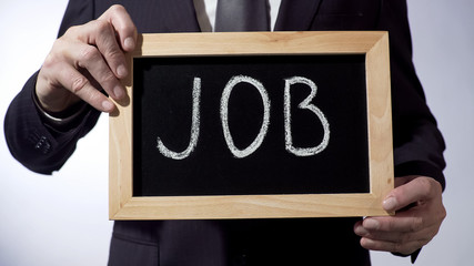 Job written on blackboard, male hands holding sign, business concept, career