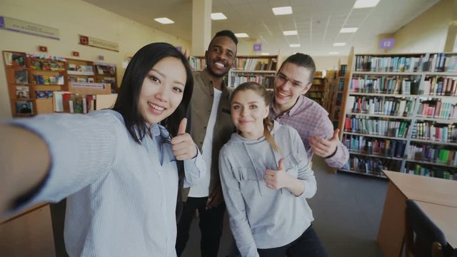 Point of view of international student group have fun smiling and taking selfie photos on smartphone camera at university library