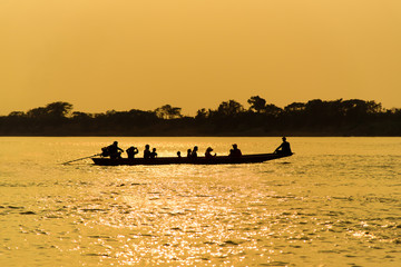 Boat ride on the river at golden sunrise, silhouette.
