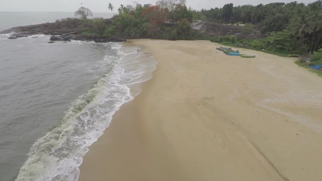An aerial view of a tropical beach in Kerala, India with palm trees.