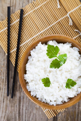 Boiled rice in a wooden bowl and chopsticks