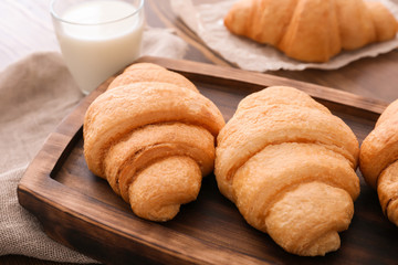 Tasty croissants on wooden tray, closeup
