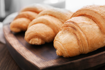 Tasty croissants on wooden tray, closeup