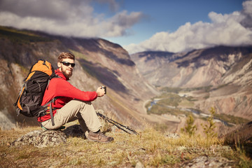 Handsome young male hiker sitting on the edge of a canyon looking away