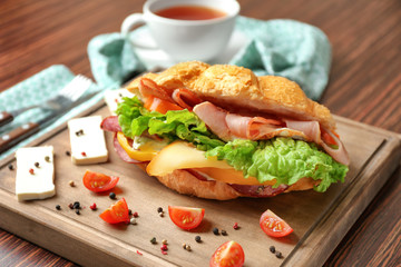 Tasty croissant sandwich on wooden board, closeup