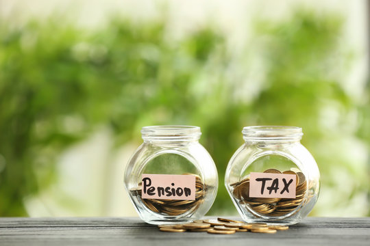 Glass jars with coins on table against blurred background. Pension planning concept