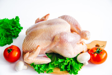 raw chicken on the cutting board, with tomatoes, garlic, mushrooms and seasonings on lettuce leaves, isolated on white background, for grilling