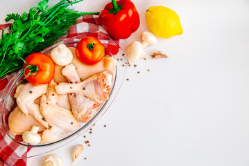 Top view chopped by piece fresh raw chicken meat on a plate with vegetables tomatoes, garlic, pepper, lemon, mushrooms and seasonings, on the kitchen towel, with place for you own text message