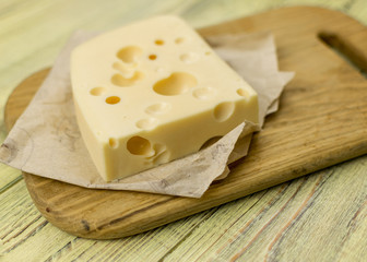 Cheese on cutting board  and knife on wooden background
