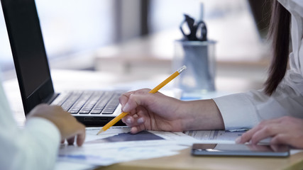 Two women discussing project and working on papers together at company office