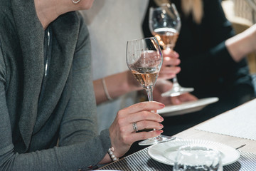 woman holds glass of red wine. people consider the color of the wine and try how it smells in different glasses