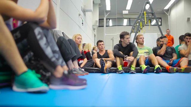 Young people sits on the floor and listening a coach on the training