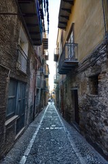 Fototapeta premium Cefalù, Italy, Sicily August 16 2015. The alleys of cefalù that wind at the foot of the fortress behind the cathedral. Steep stairways, picturesque signs. Narrow streets, flower boxes, laundry threads