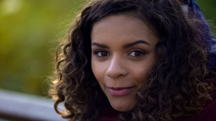 Beautiful biracial woman posing for camera and smiling sincerely, face close-up