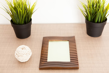 Wooden photo frame on the table next to pots of grass