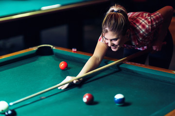 Fototapeta premium Young attractive woman playing pool in bar