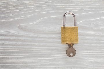 Locked padlock with silvered keys on white wooden background. Estate and security concept with...