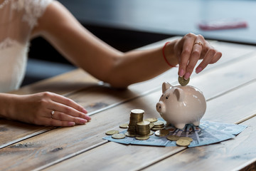 The bride counts the money. Wedding expenses. Bride with a piggy bank