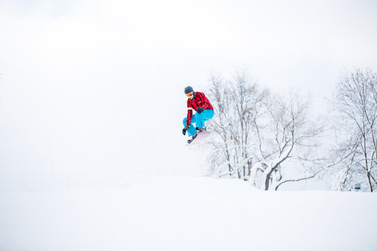 Photo of snowboarder man jumping on snowy hill