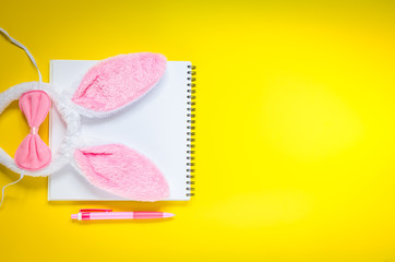 Easter holiday background with notebook, pen and bunny ears