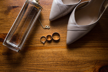 Golden wedding rings, bridal shoes and perfume on brown background. Bridal accessories.