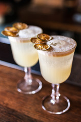 Two white cocktails with dried lime on the bar