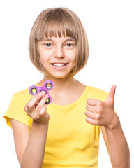 Young girl holding popular fidget spinner toy - close up portrait. Happy smiling child playing with...