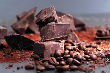 Broken dark chocolate, cocoa powder and coffee beans on a wooden table
