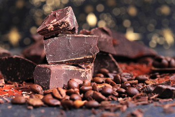 Broken dark chocolate, cocoa powder and coffee beans on a wooden table