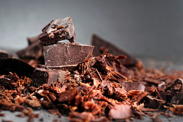 Broken dark chocolate, cocoa powder and coffee beans on a wooden table